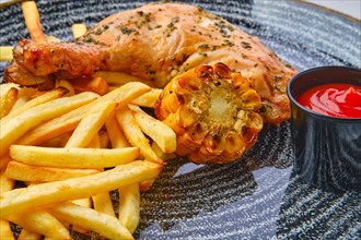 Close up view of baked chicken thigh with french fries