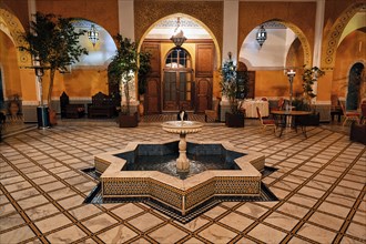 Illuminated courtyard with ornate star-shaped fountain in a riad