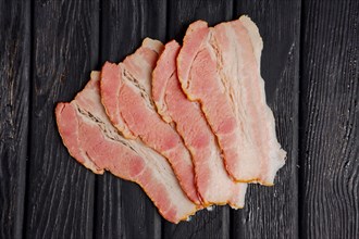 Top view of slices of fresh bacon on wooden table
