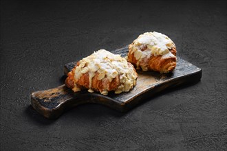 Crispy croissant with caramel and peanut shavings on wooden serving board