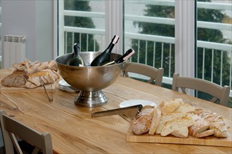 A table with cutted bread with seeds on wooden board and cold basket with ice and champagne