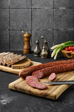 Smoked pork sausage rings on wooden cutting board on kitchen table