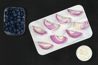 Top view of frozen pierogi with blueberry and sour cream