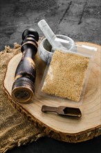 Wooden cross section with garlic in plastic package and stone mortar and mill