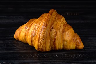 Fresh golden croissant on black table