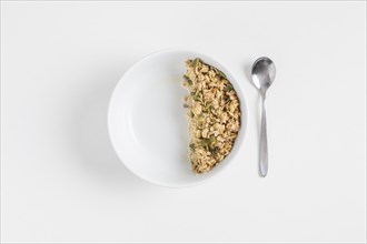 Granola with pumpkin seeds white bowl spoon white background