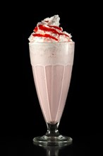 Milkshake cherry summer cocktail in tall facetted glass isolated on black