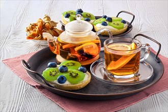 Citrus tea with cottage cheese on fresh bun with kiwi marmalade and blueberry