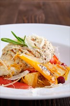 Closeup view of fried turkey meat with roasted tomato and bell pepper served with parmesan