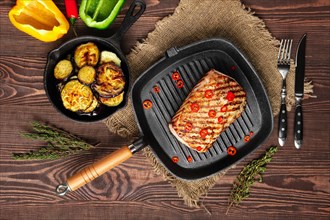 Top view of grilled striploin on grill pan and fried eggplant on wooden background