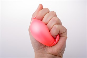 Squeezing pink balloon with hand on a white background