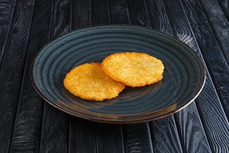 Portion of fried potato pancakes on dark wooden table