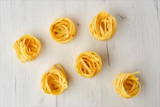 Overhead view of raw tagliatelle on wooden table