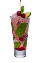 Pouring cherry juice to alcoholic cocktail with lime and mint isolated on white