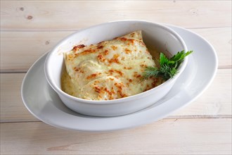 Thin pancakes with stuffing baked in oven with melted cheese