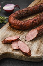 Smoked pork sausage with spices on wooden cutting board