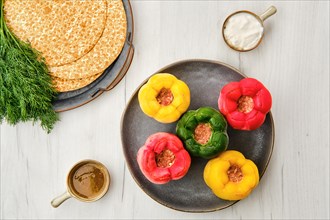 Top view of colorful bell pepper stuffed with meat and rice on white wooden table