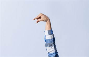 Hand gesturing the letter Q in sign language on an isolated background. Man's hand gesturing the letter Q of the alphabet isolated. Letter Q of the alphabet in sign language