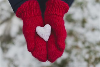 Gloved hands holding white heart