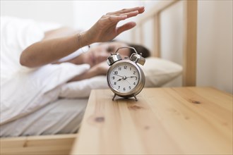 Woman turning off alarm clock while lying bed. Resolution and high quality beautiful photo