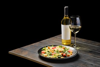 Salad with chicken and fresh vegetables with a wine on a table