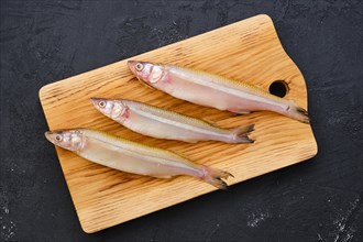 Top view of raw fresh smelt fish on wooden cutting board