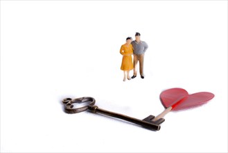 Couple standing in front of a heart shape and a key on a white background