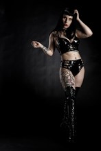 Woman with black hair and tattos in vinyl and latex outfit