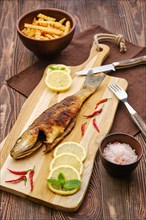 Fried sea bass with fried potato on wooden cutting board