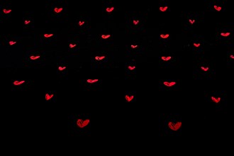 Black fabric background with red hearts shapes