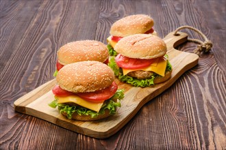 Four homemade burgers on wooden serving board