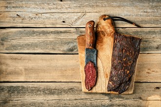 Top view of smoked dried beef meat and slice on wooden cutting board