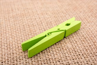 Green wooden clothespin on a textured background on display