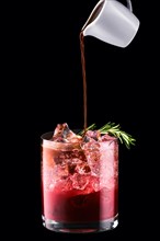 Pouring espresso in tonic with cherry juice isolated on black background