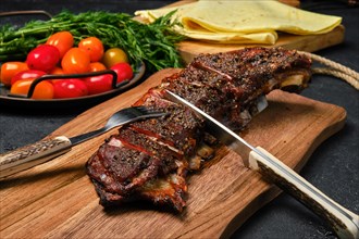 Close up view of grilled lamb breast and flap on wooden cutting board