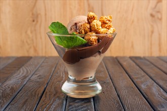 A cup of chocolate ice cream decorated with caramel popcorn and mint leaves