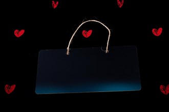 Rectangular shaped black notice board and red hearts on black background