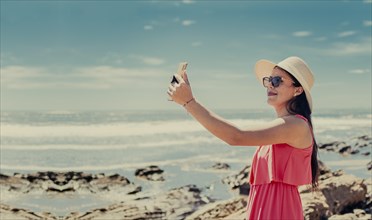 Young woman on vacation taking photos on the beach