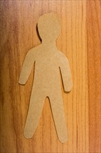 Man shape cut out of paper on wooden texture