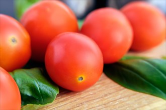 Macro photo of fresh tomato cherry with basil on wooden cutting board. Soft focus photo with shallow depth of field