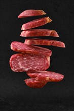 Levitating slices of smoked beef sausage over black background