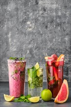 Three glasses with fruit refreshing drink on gray shabby background
