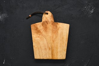 Empty wooden cutting board on black shabby background