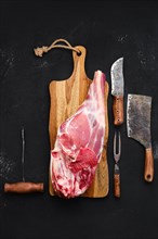 Fresh raw lamb leg bone in on wooden cutting board