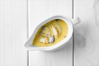 Mushroom sauce in ceramic gravy boat on white wooden table