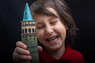 Little boy holding a model of the Galata Tower in Istanbul