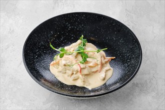 Pieces of chicken meat with bell pepper and creamy white sauce on a plate