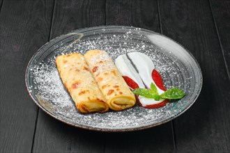 Thin crepe with ricotta and strawberry jam on a plate
