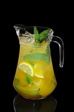 Cold Lemon and mint cocktail with a sparkling wine with ice cubes in pot isolated on black