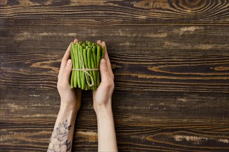 Overhead view of fresh green beans in hand over wooden background